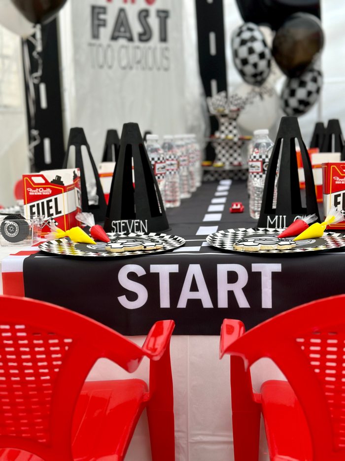 Racing themed birthday table with red chairs and checkered decorations